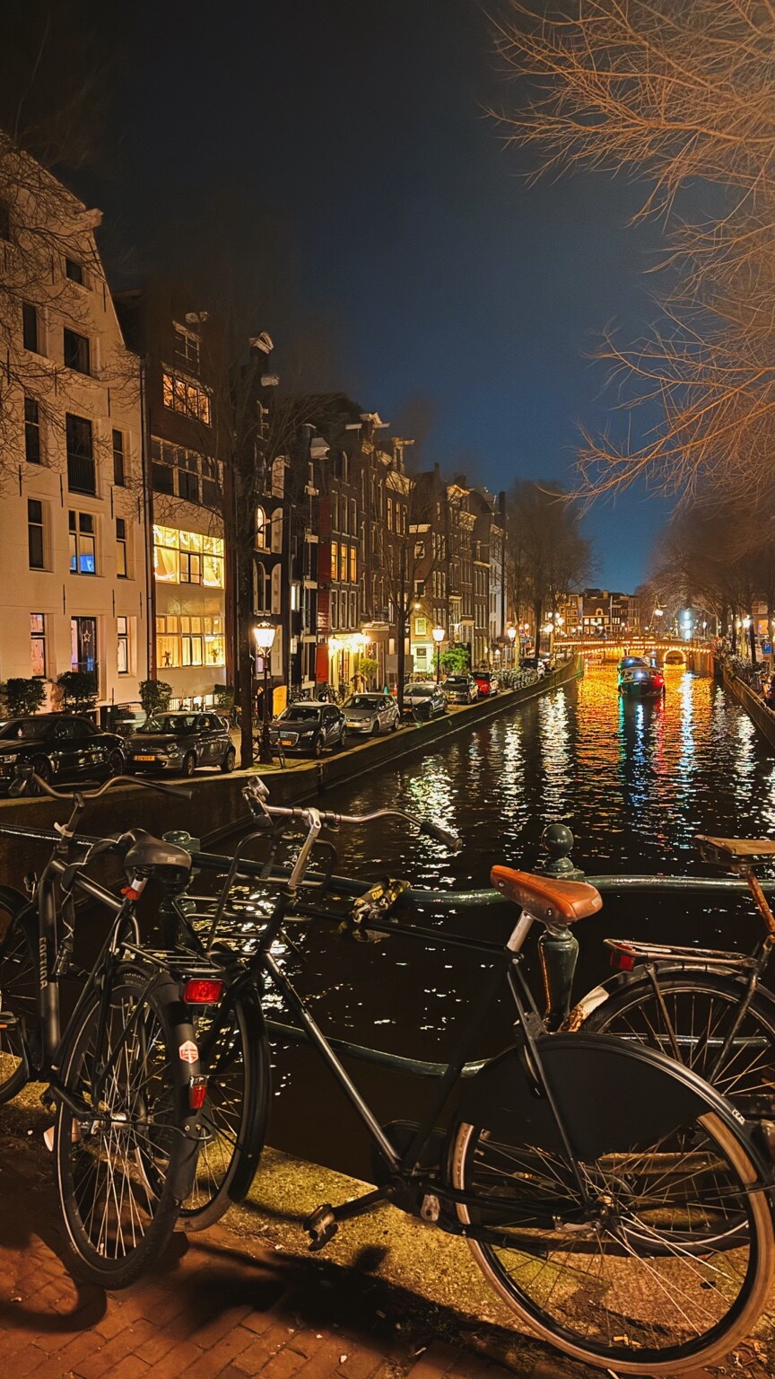 Amsterdam canal at night with bicycles in the foreground