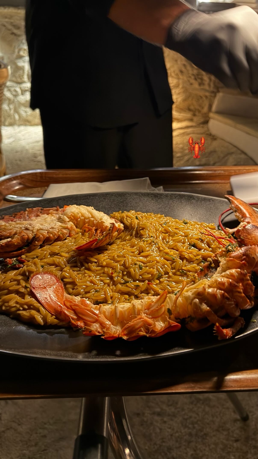 A large platter of lobster with orzo being brought to the table